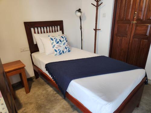 a bed with a blue and white pillow on it at Zee Golf Affordable Luxury in Galle