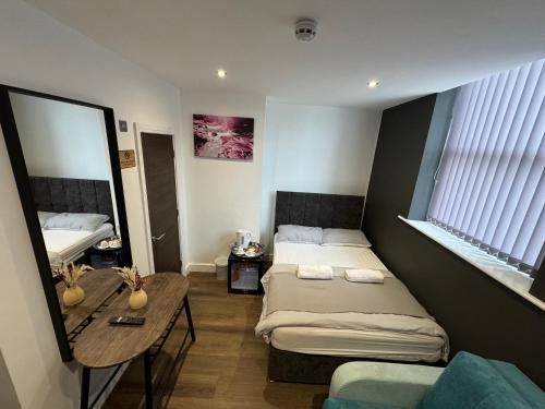 a bedroom with two beds and a table and a mirror at Southgate Luxury Apartments-Jaquzzi Bath-Private Parking- 2 Min M62 in Elland