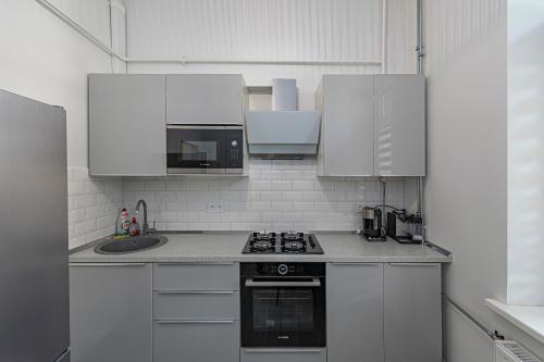 a kitchen with white cabinets and a stove top oven at Riverside 1 BD Central Apartment by Hostlovers in Kaunas