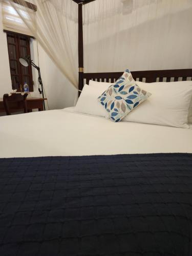 a white bed with a blue and white pillow on it at Zee Golf Affordable Luxury in Galle