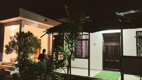 a woman standing in front of a house at night at Munroe Heritage Inn in Munroe Island