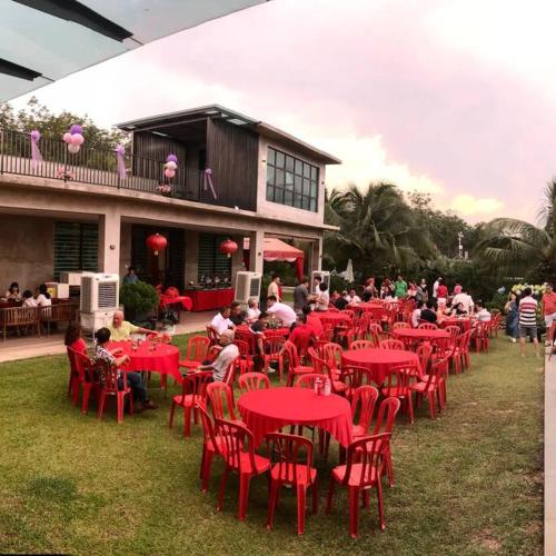 a group of people sitting at red tables in front of a building at U House Exclusive Retreat in Alor Gajah in Kampong Alor Gajah