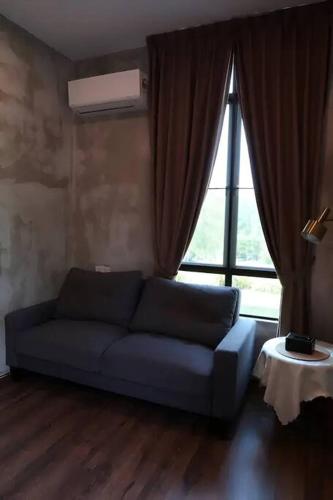 a living room with a blue couch and a large window at U House Exclusive Retreat in Alor Gajah in Kampong Alor Gajah