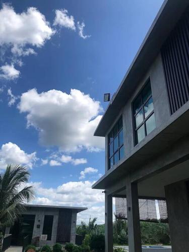 a building with a palm tree and a cloudy sky at U House Exclusive Retreat in Alor Gajah in Kampong Alor Gajah
