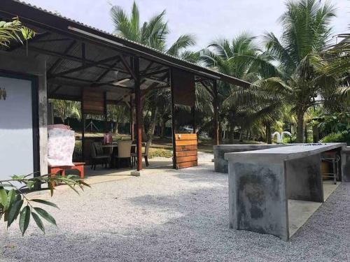a pavilion with a table and chairs and palm trees at U House Exclusive Retreat in Alor Gajah in Kampong Alor Gajah