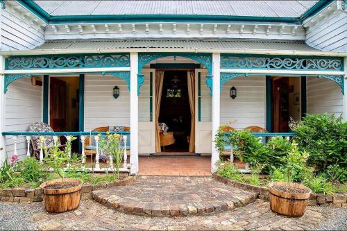 a front porch of a house with a blue roof at Karamana Homestead (1872) in Coromandel Town