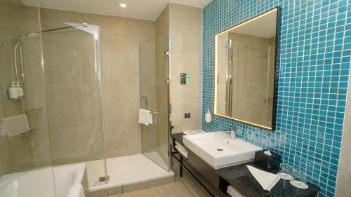 a bathroom with a sink and a shower and a tub and a mirror at Holiday Inn Tashkent City by IHG in Tashkent
