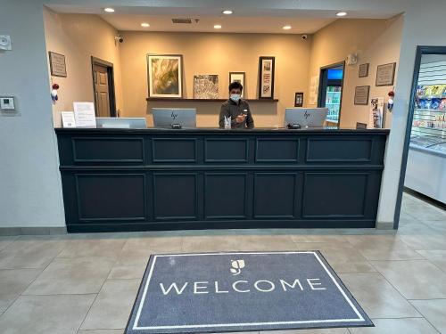 a person wearing a mask standing at a counter in a store at Country Inn & Suites by Radisson, Chicago O'Hare South, IL in Bensenville