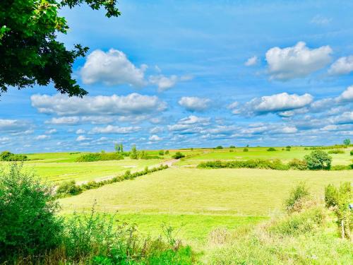 a field of green grass with a blue sky and clouds at Domaine de falimont à Labuissière in Merbes-le-Château