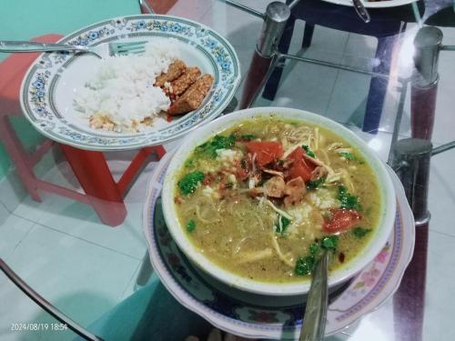 a bowl of soup and a plate of rice on a table at Petra Homestay Bangka Leda in Ruteng
