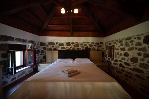 a bedroom with a bed with two towels on it at Villa & Stone House with Pool, 10 Mins to Skala Eressos Beach in Eresos