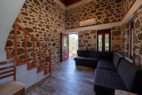 a living room with a couch and a stone wall at Villa & Stone House with Pool, 10 Mins to Skala Eressos Beach in Eresos