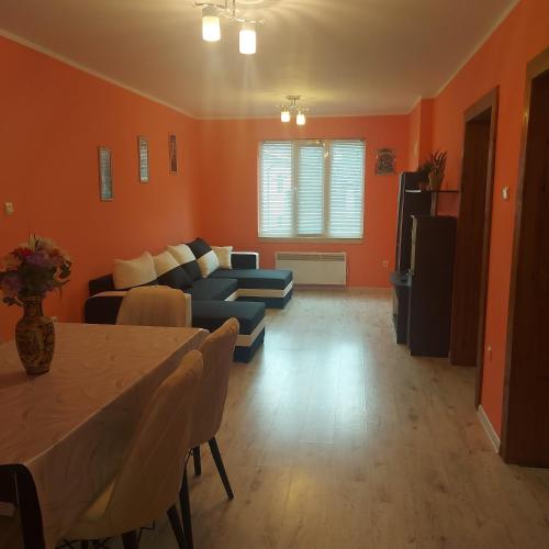 a living room with orange walls and a blue couch at Viktoria House in Sapareva Banya