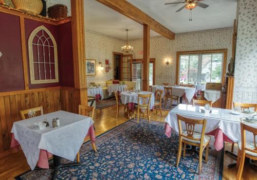 a dining room with white tables and chairs at Rockwell Falls Inn and Wine Bar in Lake Luzerne