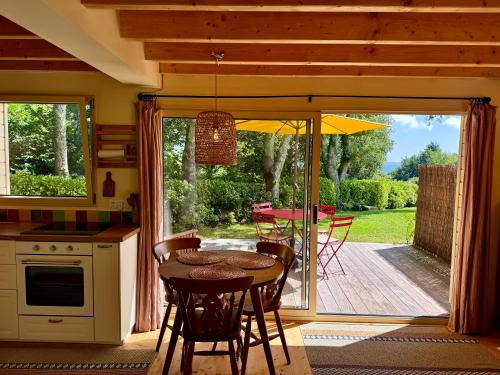 a kitchen with a table and chairs and a patio at Chalet Cormoran, face à l'océan in Fouesnant