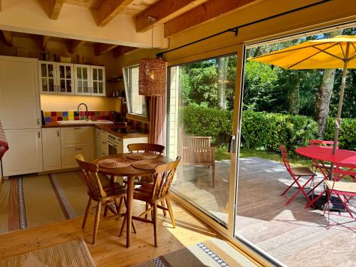 - une cuisine avec une table, des chaises et un parasol dans l'établissement Chalet Cormoran, face à l'océan, à Fouesnant