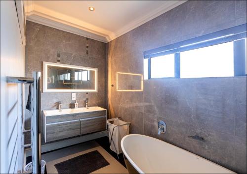 a bathroom with a tub and a sink and a mirror at Pelicans Nest in Onrus in Hermanus