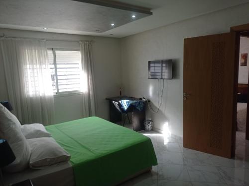a bedroom with a green bed and a window at Sala Al Jadida - Appartement meublé à 5 min de Technopolis et 13 min de l'aéroport in Oulad Yakoub