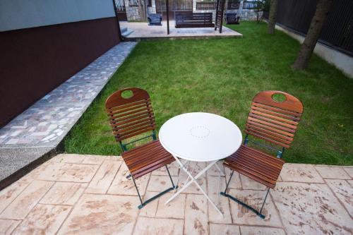 a table and two chairs with a white table in a yard at Cuibul Zăganului - Relax, Sauna & SPA in Cheia