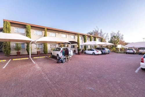 a building with cars parked in a parking lot at Auas City Hotel in Windhoek