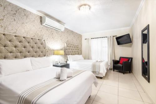 a hotel room with two beds and a chair at Auas City Hotel in Windhoek