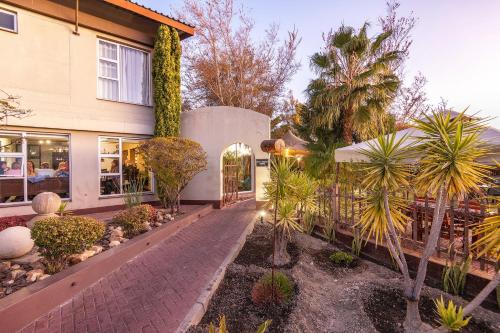 a house with palm trees and a brick walkway at Auas City Hotel in Windhoek