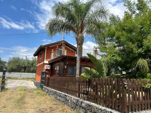 a house with a palm tree in front of a fence at Villetta Due Palme - vicino GIARDINI NAXOS - in Calatabiano