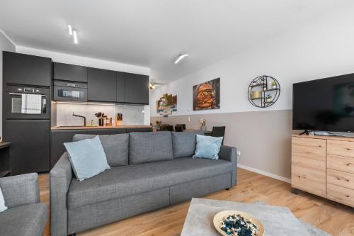 a living room with a gray couch and a kitchen at Design Luxus, Vollausstattung, Neubau, 30min Hbf Leipzig 8, Nähe Flughafen, BMW, DHL, Amazon in Schkeuditz