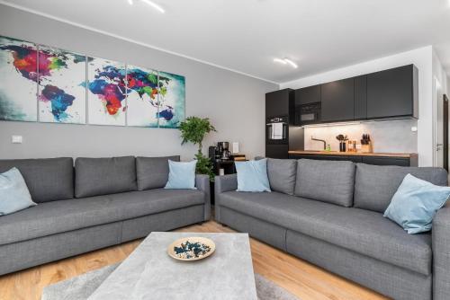 a living room with two gray couches and a kitchen at Design Luxus, Vollausstattung, Neubau, 30min Hbf Leipzig 8, Nähe Flughafen, BMW, DHL, Amazon in Schkeuditz