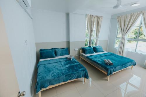 a bedroom with two beds with blue sheets and windows at Kings Pine Residence homestay 14 in Ranau