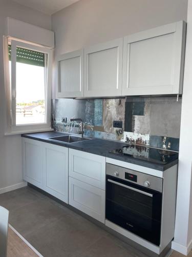 a kitchen with white cabinets and a sink and a window at Il balcone sul mare in Porto Recanati