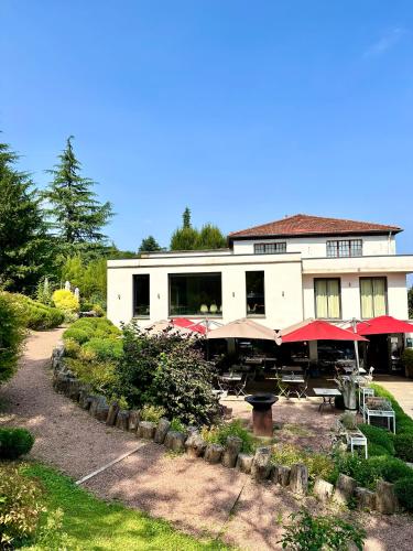 un bâtiment avec des tables et des parasols devant lui dans l'établissement Le Clos Jeannon, à Nancy