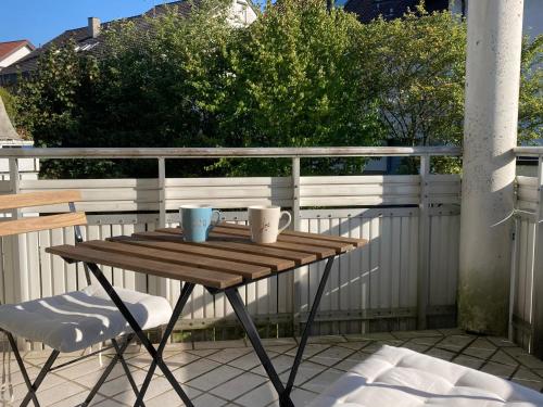 a wooden table with two mugs on a balcony at Studio-Priv.Parkplatz-Balkon-Wlan-Netflix-SmartTV in Deizisau