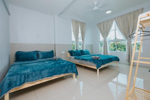 a bedroom with two beds with blue sheets and a window at Kings Pine Residence homestay 14 in Ranau