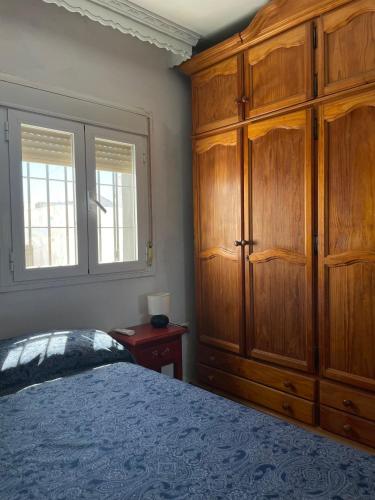 a bedroom with a large wooden cabinet and a bed at Apart Centro-Playa Terraza in Barbate