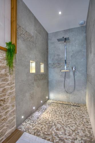 a shower in a bathroom with a stone wall at Rêverie en Périgord du Domaine des Hauts de Rouquette in Eymet