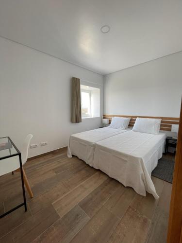 a bedroom with a large white bed and a desk at Quinta da Mouracha in Águas