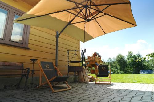 an umbrella and chairs on a patio with a house at Pod Hawraniem Ski & Bike Friendly in Jurgów