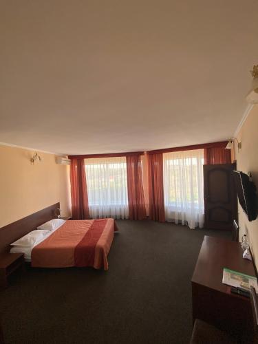 a hotel room with a bed and a flat screen tv at Belveder in Rohatyn
