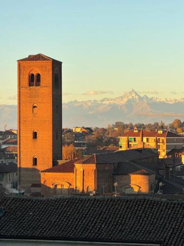 a building with a clock tower with mountains in the background at Bricks House in Chieri