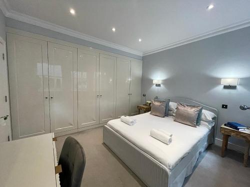 a bedroom with a bed with white cabinets and a desk at The Cadogan Suite by Harrods in London
