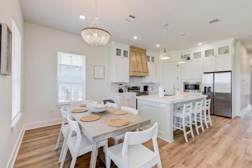 a white kitchen with a table and white chairs at Salt & Stone Villas in Galveston