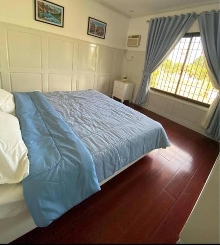 a bedroom with a blue bed and a window at Elle Casa is a modern-European inspired house coc in San Pablo