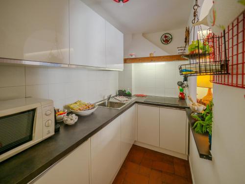 a kitchen with white cabinets and a microwave at La Maison de la Mer with Terrace and AC in Vernazza