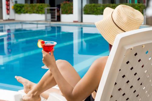 a woman sitting in a chair with a drink in front of a pool at Hotel Caquetá Real HSC in Florencia