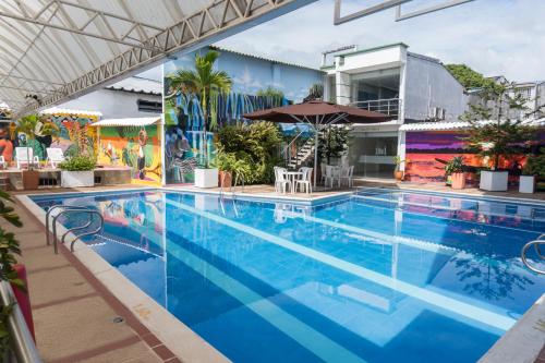 a large blue swimming pool with an umbrella at Hotel Caquetá Real HSC in Florencia