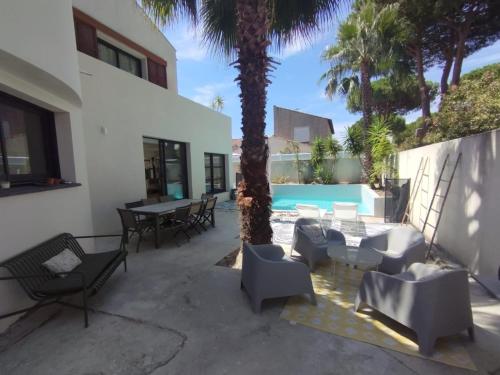 une terrasse avec des chaises, une table et un palmier dans l'établissement Villa Golf LGM, à La Grande Motte