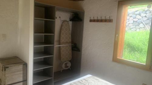 Cette chambre comprend un placard avec des étagères et une fenêtre. dans l'établissement Maison insolite de mi-montagne, à Pébrac