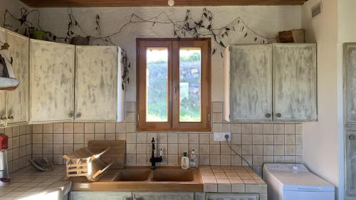 une cuisine avec un évier et une fenêtre dans l'établissement Maison insolite de mi-montagne, à Pébrac