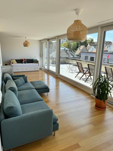 a living room with a blue couch and a large window at Exclusive Rooftop Duplex Penthouse - 200sqm - 280 Panoramic Views - Downtown in Basel